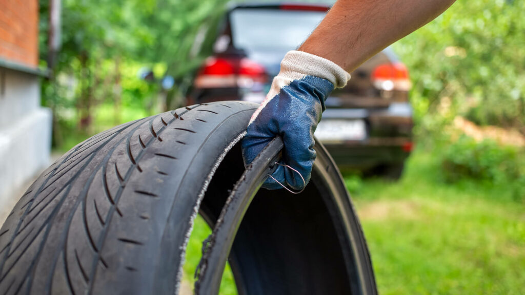 Man holding a defective tire that has de-treaded - Texas Product Liability Attorneys