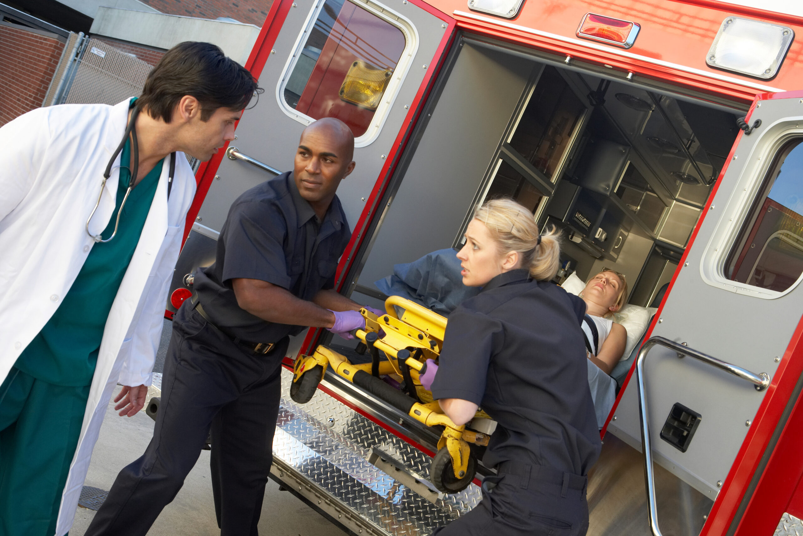 Paramedics and doctor unloading patient from ambulance.