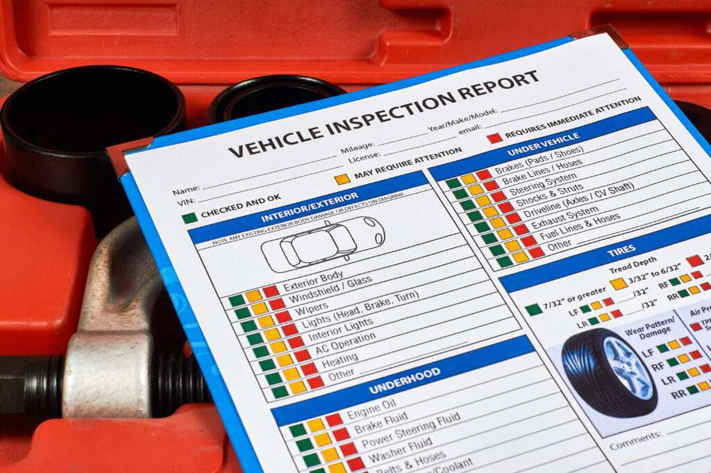 Vehicle vehicle inspection report form against the background of automotive tools. Close up.- Vehicle Inspection Laws by State