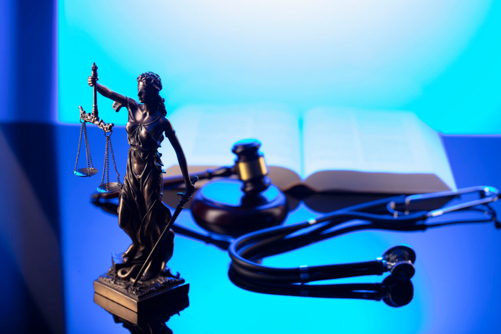 Do Personal Injury Lawyers Handle Medical Malpractice Claims? 3 Medical malpractice law concept. Gavel, Themis, legal code and stethoscope on the glass table. Blue light.