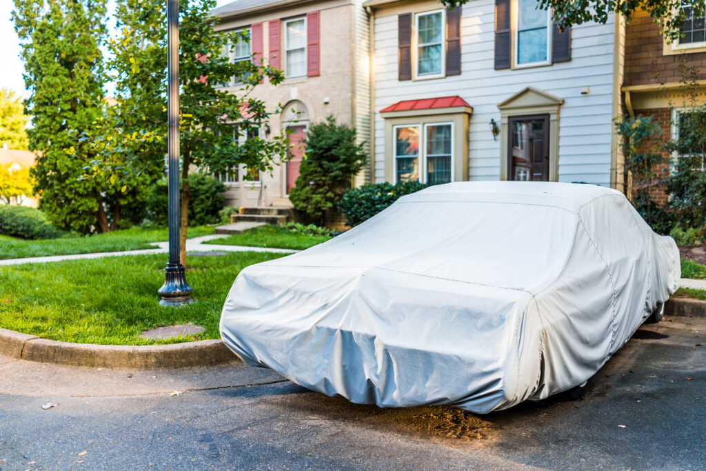 7 consejos para cuidar tu coche durante la cuarentena por coronavirus 2 Coche antiguo cubierto con funda protectora por casa adosada para clima húmedo en estacionamiento