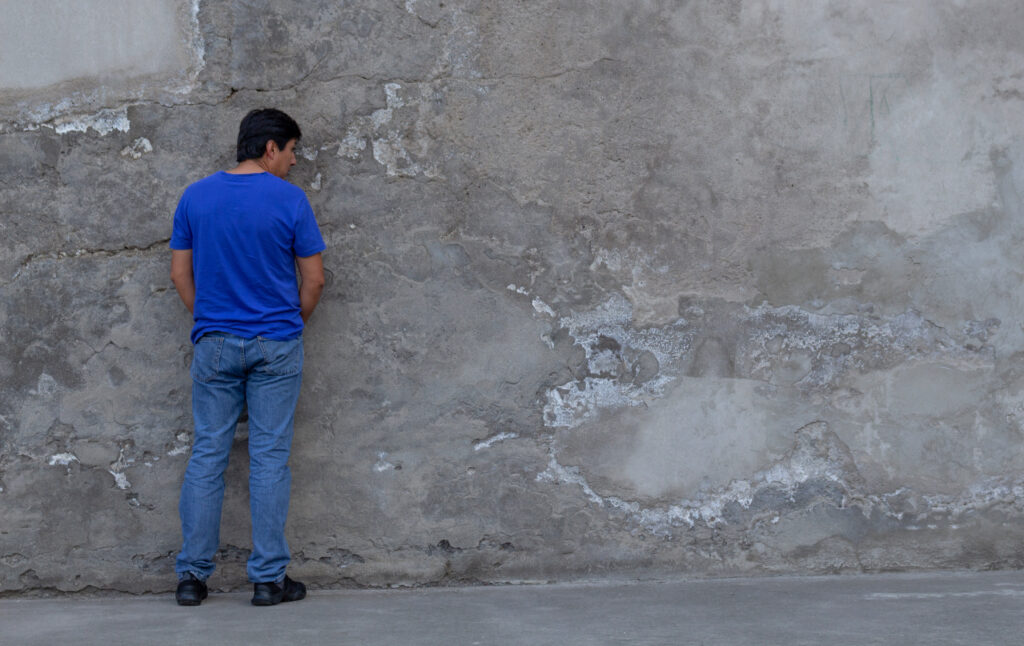 Vista general de un hombre con jeans que orina en la calle. ¿Es ilegal orinar en público en Texas?